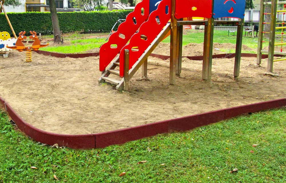 Cordolo ECO-BORDER rosso installato lungo il perimetro di un’area giochi