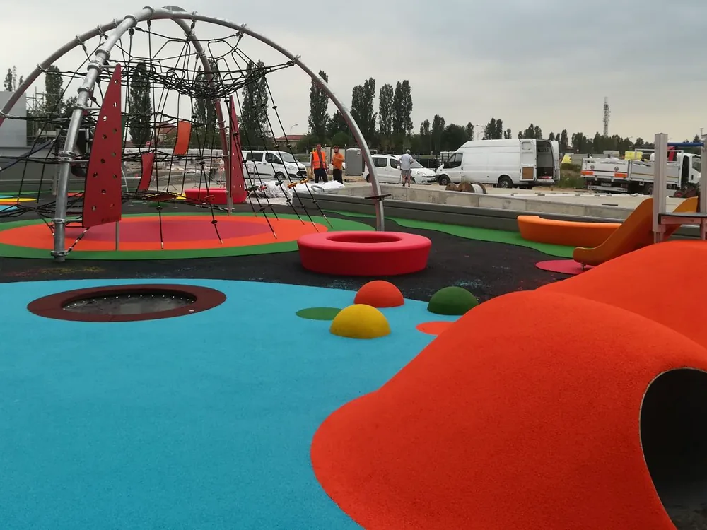 Area giochi ECO-PLANET in fase di installazione con colline colorate e rete da arrampicata